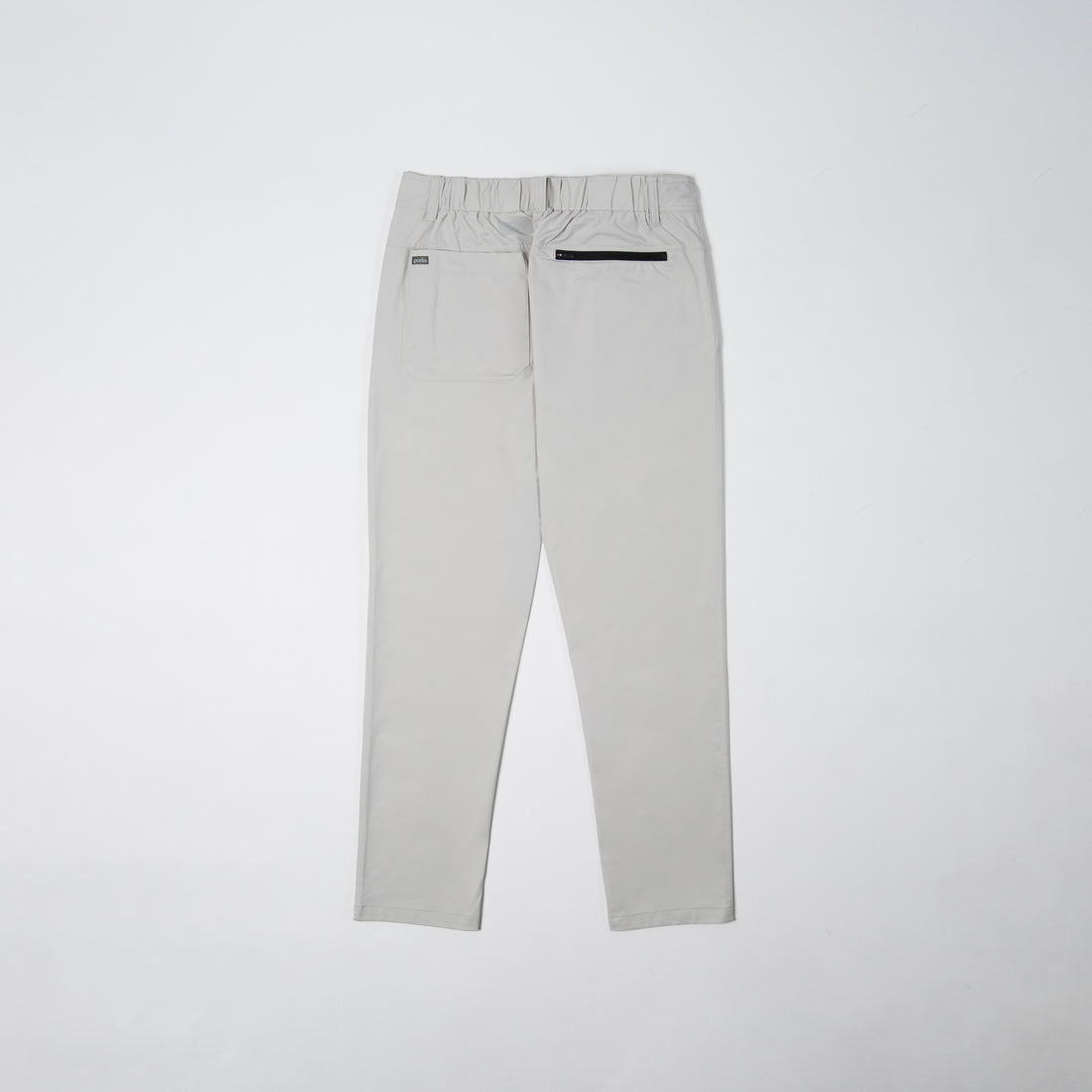 Poda project pants in limestone color, showing back zip pocket and logo patch