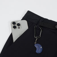 Phone case with carabiner and moon charm attached to black pants on a white background